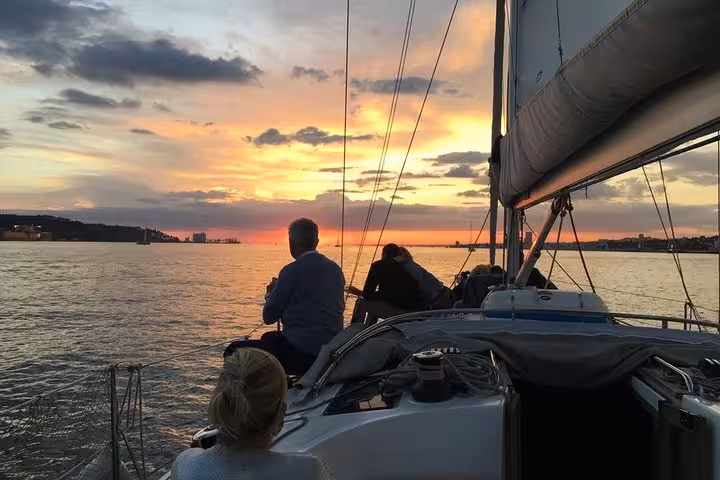 Woman watching ocean sunset from a private Cascais sailboat, 2-hour sunset cruise with drinks included