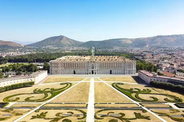 Aerial view of the Royal Palace of Caserta and formal gardens on a sunny day, visited on a private guided shuttle tour