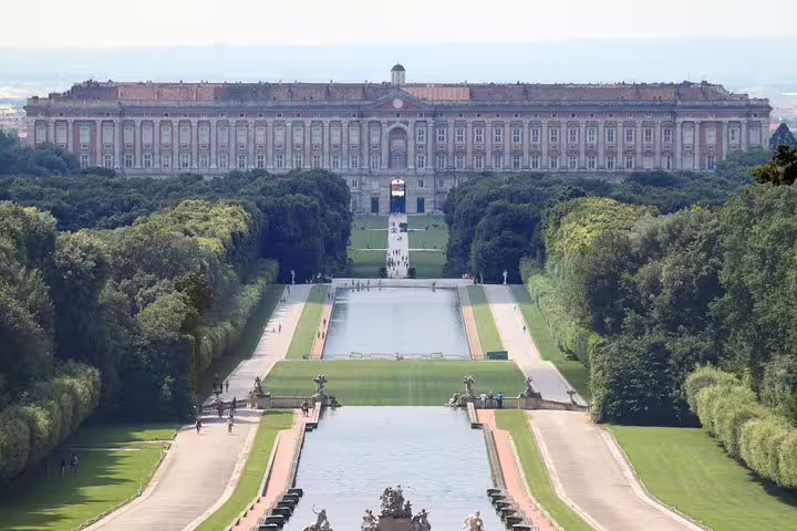 Panoramic view of the Royal Palace of Caserta and its formal gardens with long fountains seen on a guided small-group tour