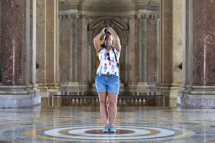 Visitor photographing the ornate marble hall of Caserta Royal Palace during a private guided tour with shuttle from Naples
