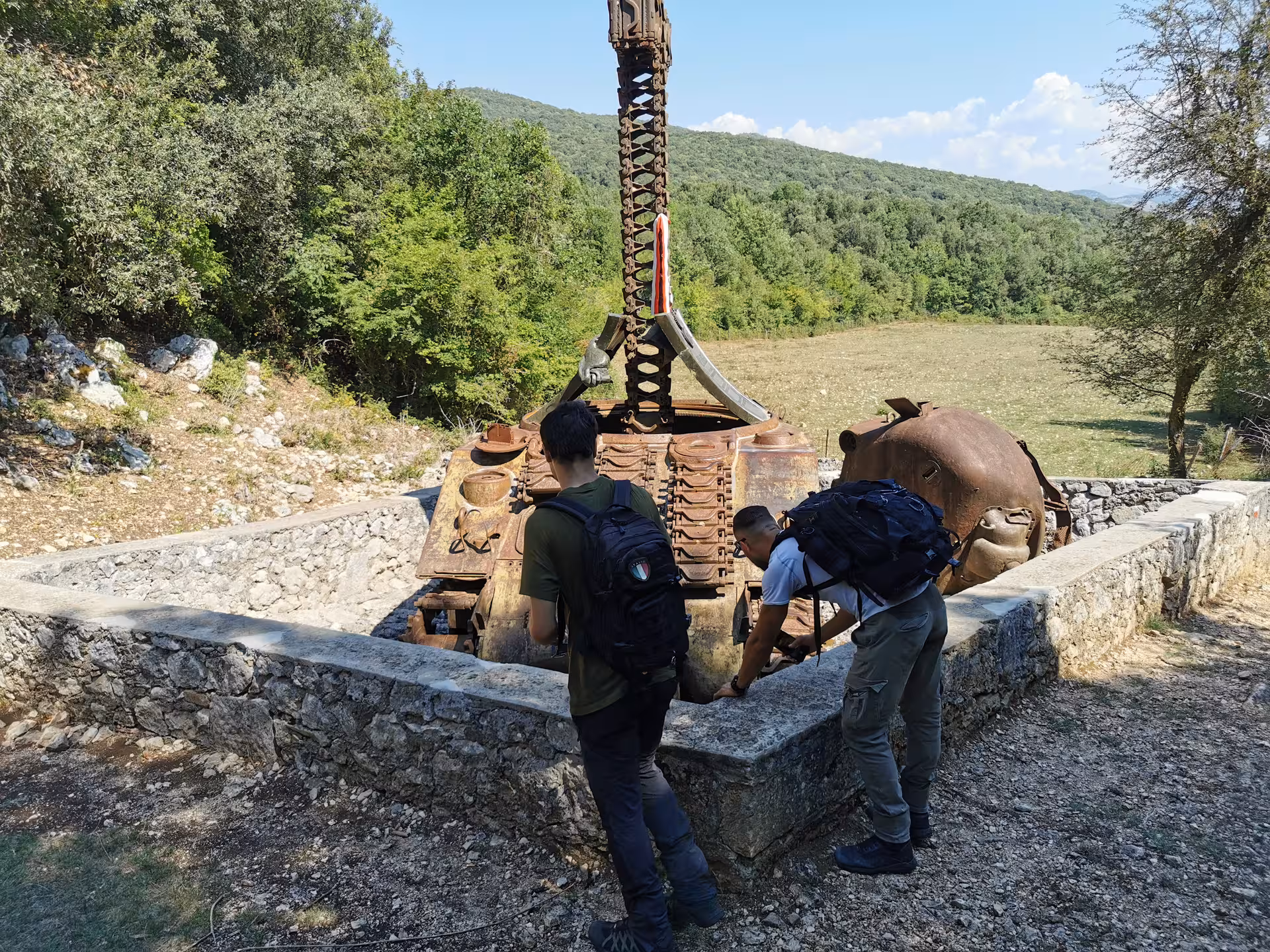 Participants examine a historic military artifact in the scenic landscape on the Cassino Red Poppy experience.