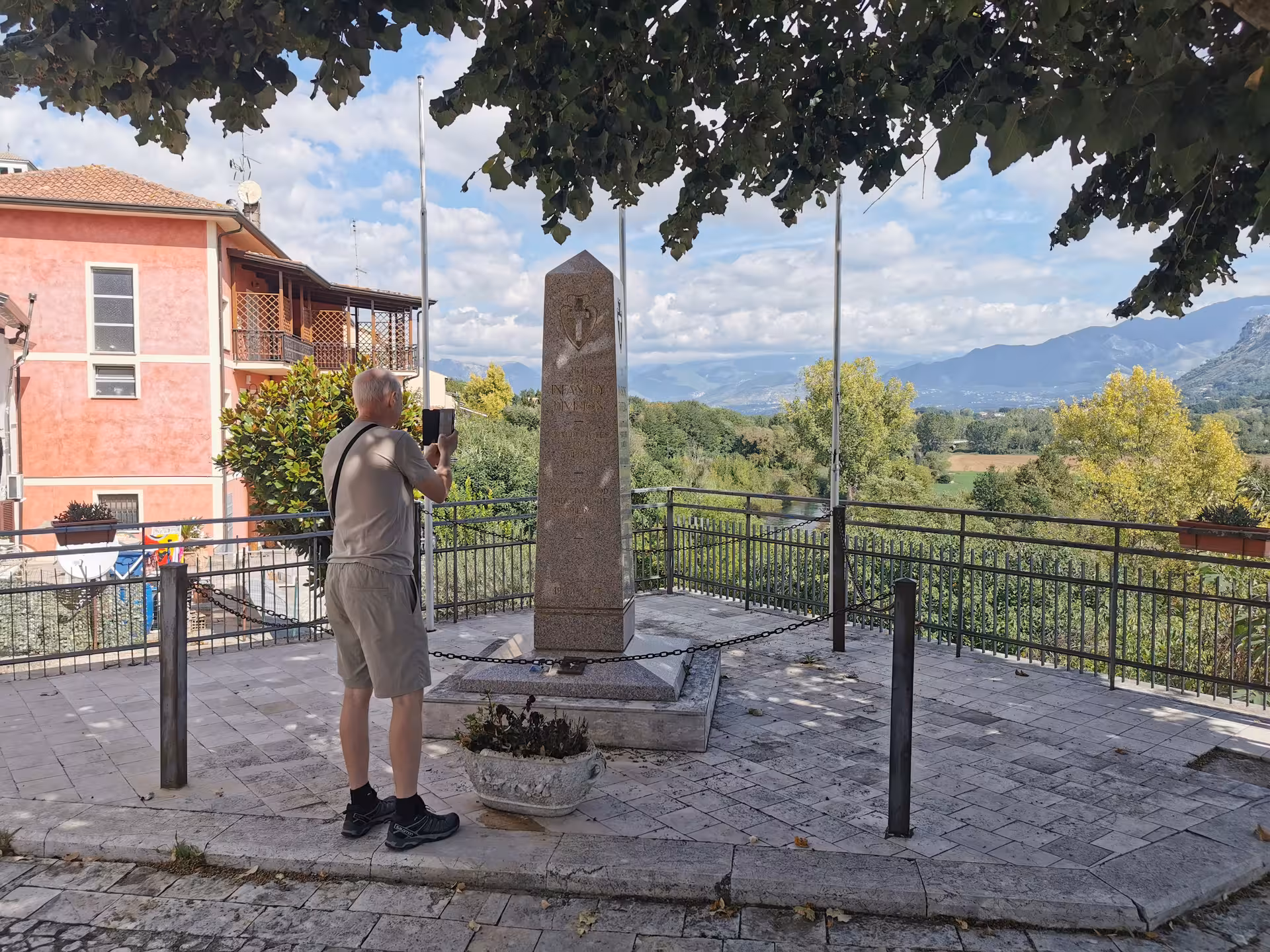 Man photographing monument in scenic Cassino setting with mountains and greenery on a tailor-made tour experience.