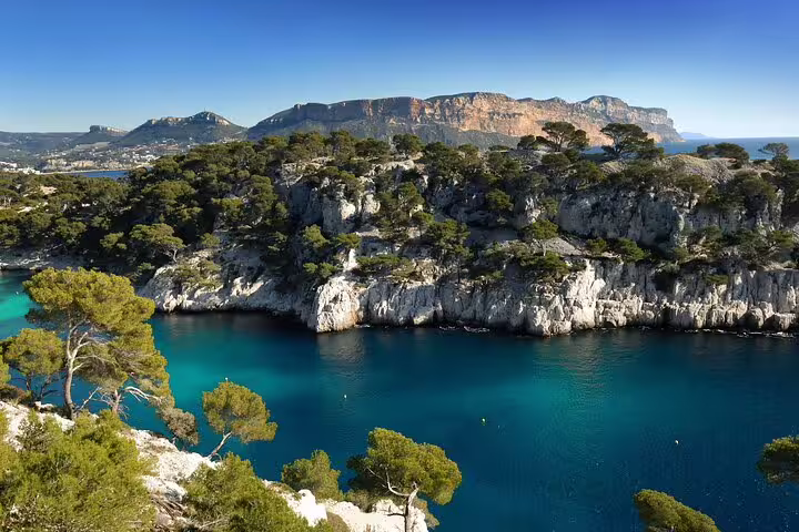 Turquoise waters of Cassis calanques with white limestone cliffs and pine trees, French Riviera