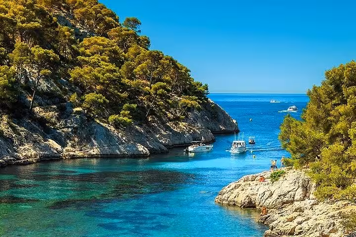 Turquoise waters of Cassis Calanques with boats nestled between rocky cliffs and pine trees