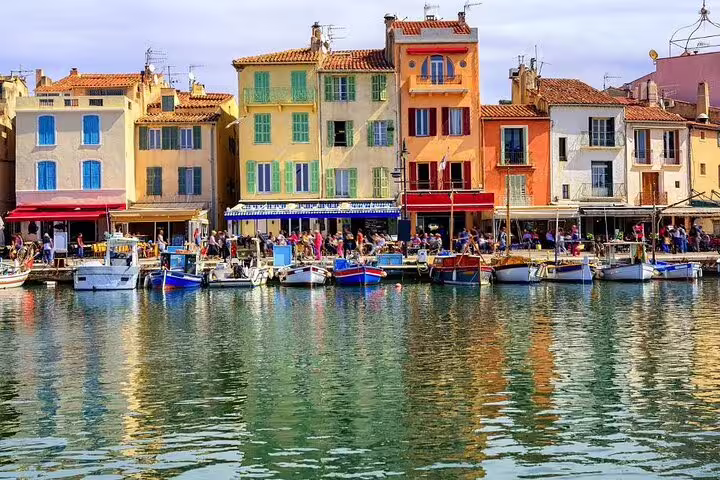 Colorful waterfront buildings and fishing boats reflected in the harbor of Cassis, French Riviera