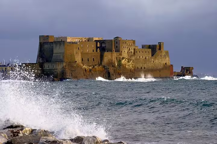 Waves crashing by Castel dell’Ovo fortress on the Bay of Naples, a highlight coastal stop on a panoramic Naples city tour
