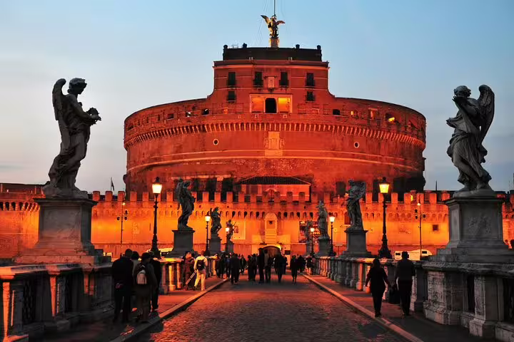 Castel Sant'Angelo illuminated at dusk with angel statues lining the bridge in Rome