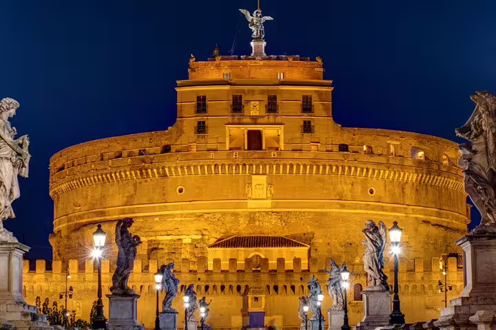 Castel Sant'Angelo illuminated at night with angel statues on bridge, Rome