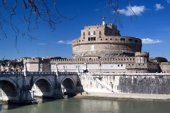 Scenic view of Castel Sant'Angelo and the Tiber River, showcasing historic architecture under a clear blue sky in Rome.