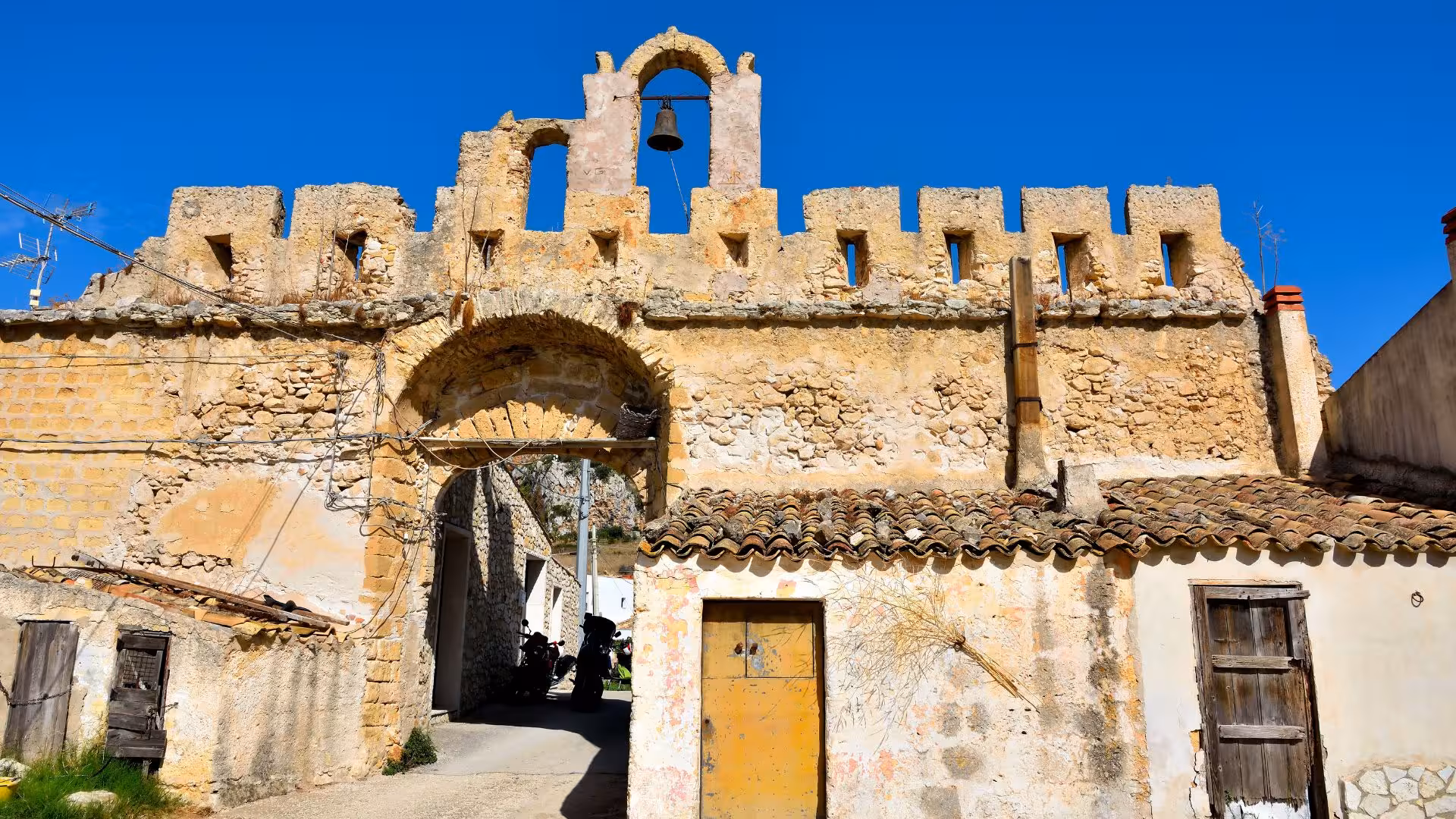 Historic stone archway with bell at Grotta Mangiapane, showcasing cultural landmarks on Castellammare del Golfo ebike tour.