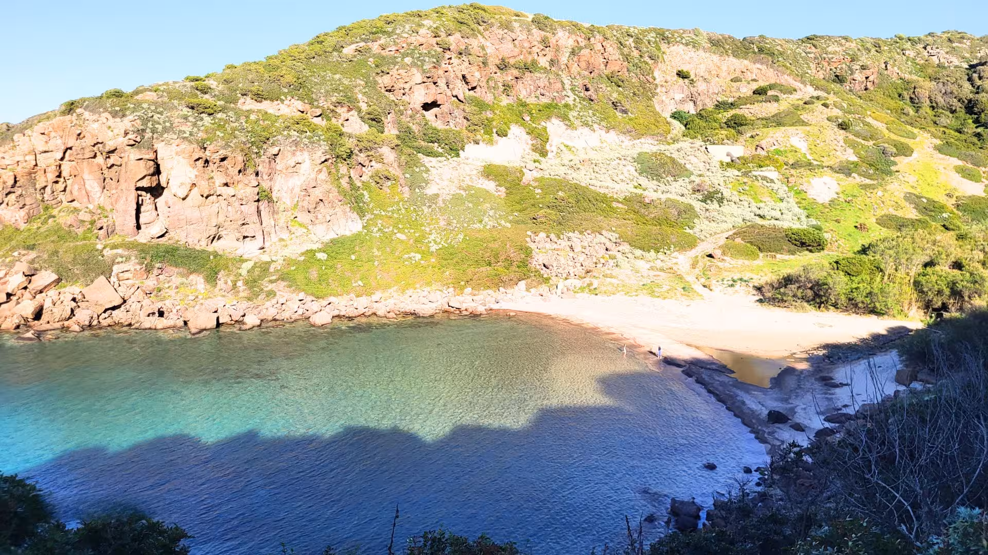 Secluded beach with clear turquoise waters and rocky cliffs in Castelsardo, a highlight of the ebike tour.