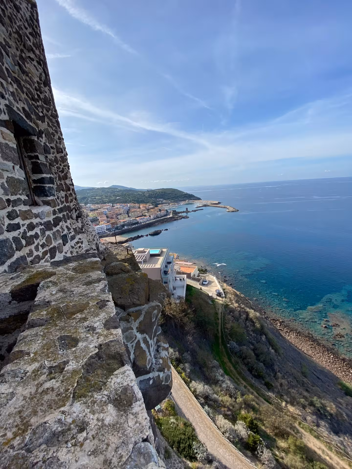 Breathtaking coastal view from Castelsardo, featuring turquoise waters and a glimpse of the town's architecture.