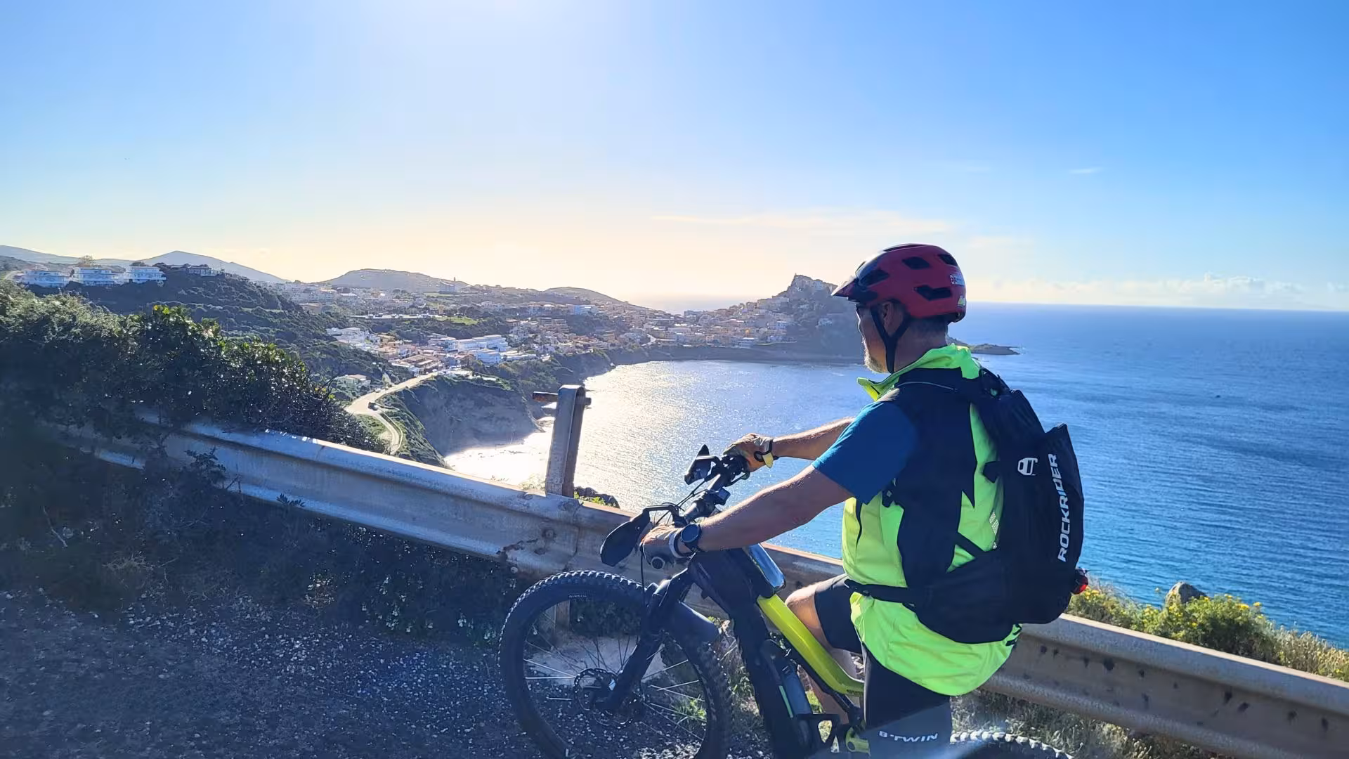 Cyclist enjoys stunning coastal views of Castelsardo during a panoramic e-bike tour under a clear blue sky.