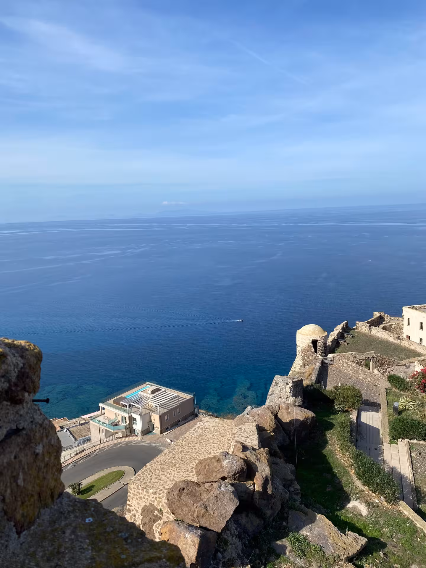 Panoramic coastal view from Castelsardo's historic fortress, showcasing the clear azure waters below.