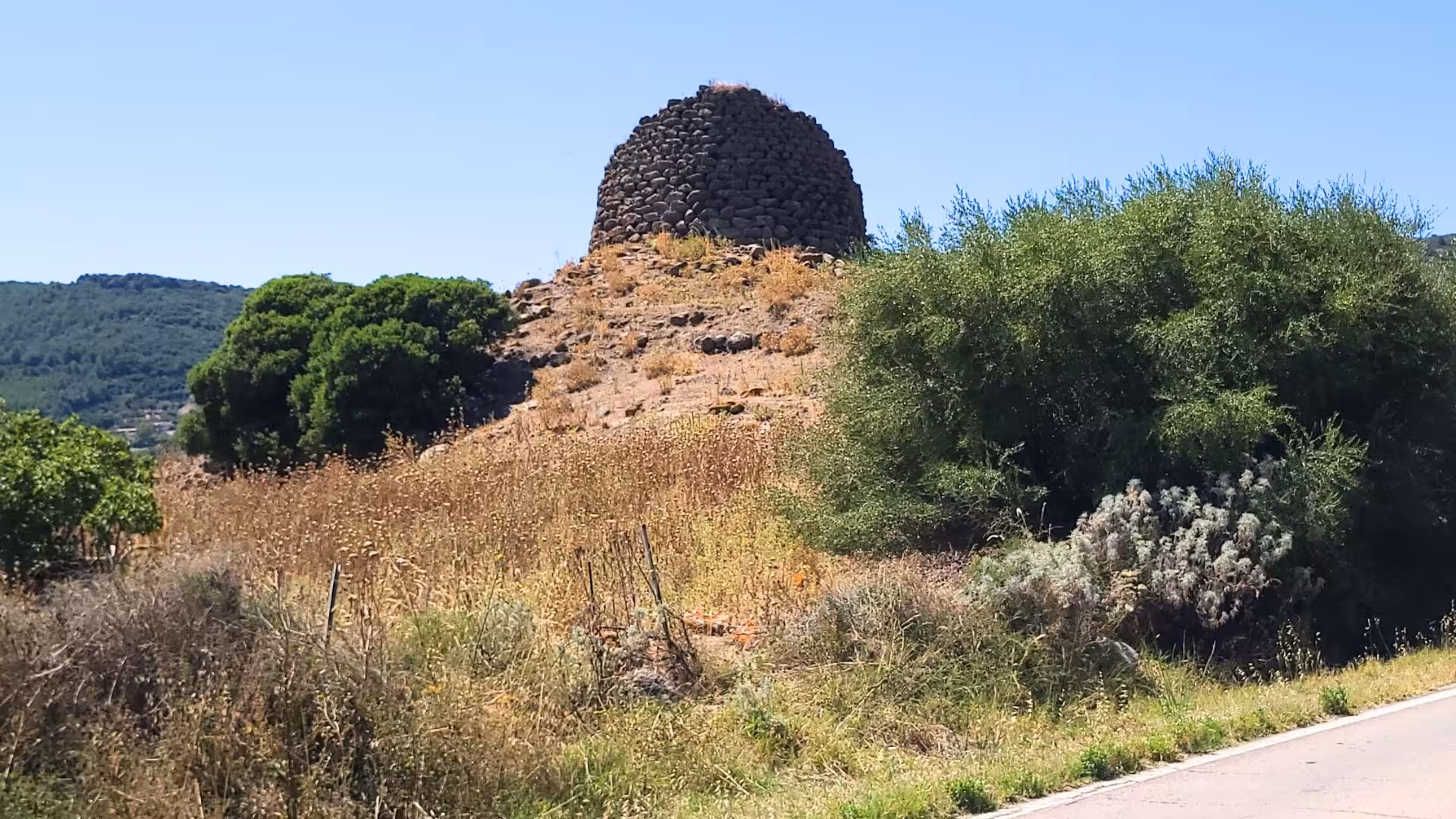 Historic stone nuraghe amidst lush vegetation in Castelsardo, a highlight of the panoramic ebike tour.