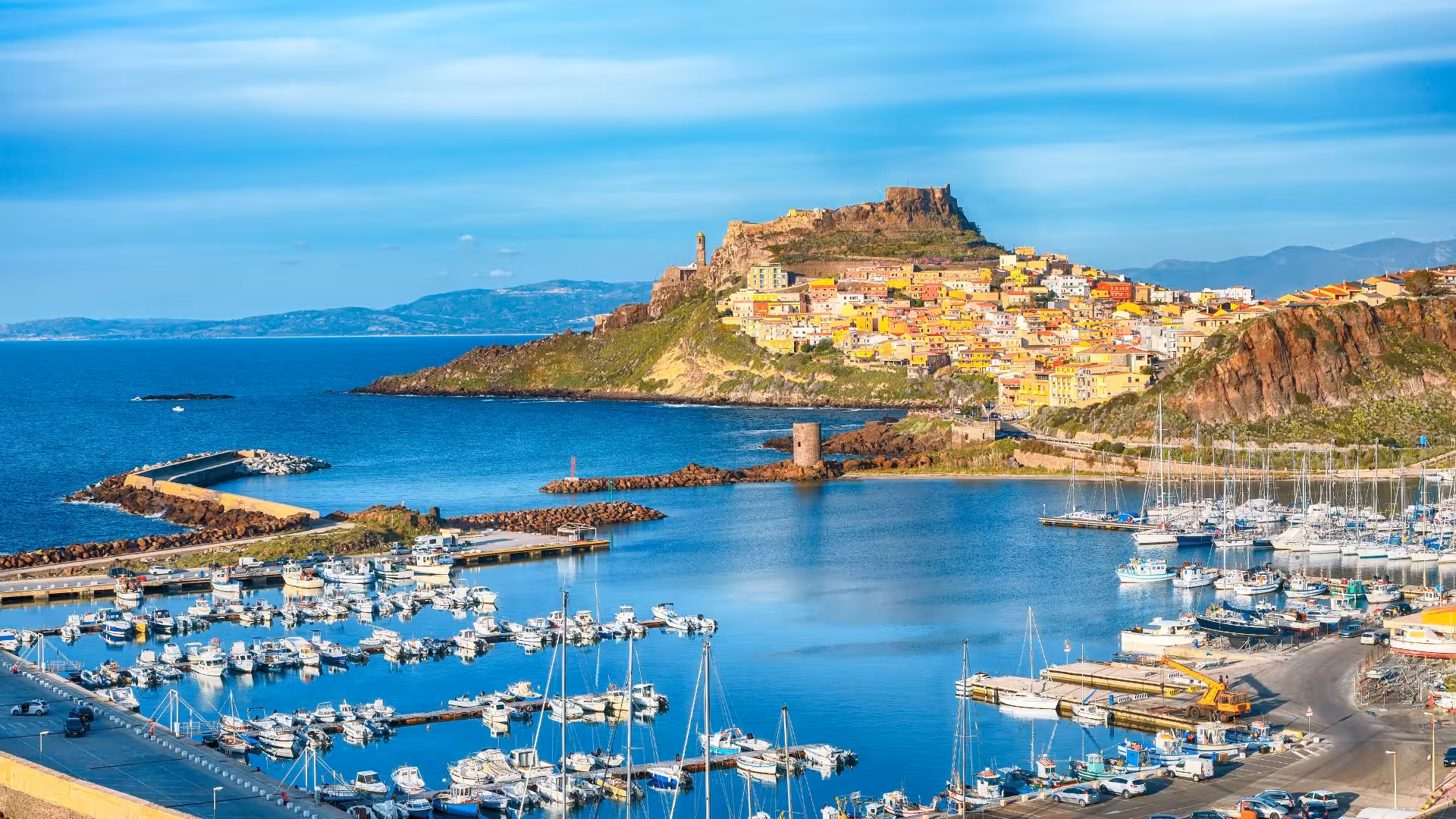 Aerial view of Castelsardo's vibrant old town and marina set against a stunning coastal backdrop.