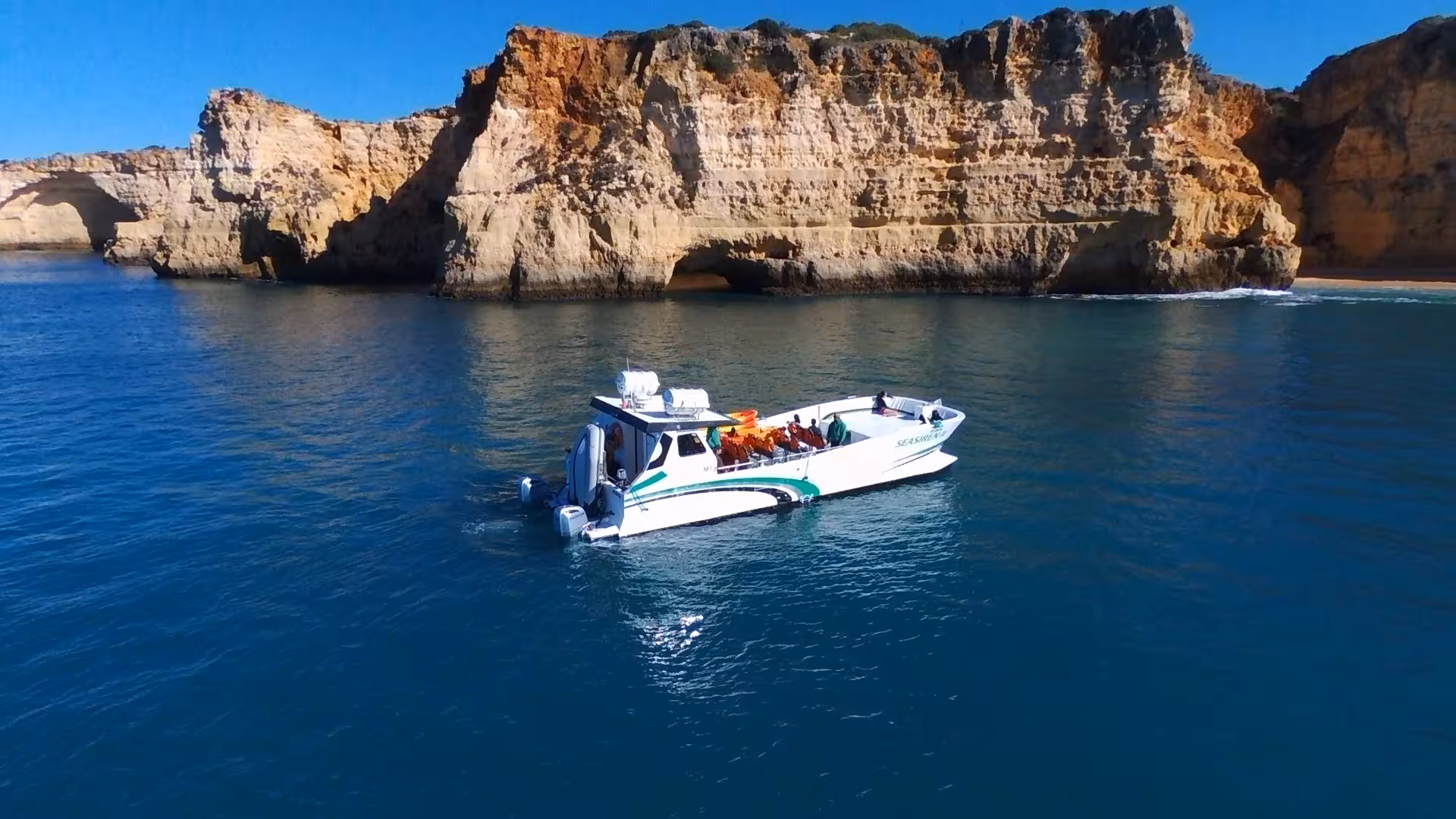 Modern catamaran cruising past Benagil sea caves and dramatic Algarve cliffs on a private tour to Marinha Beach, Portugal