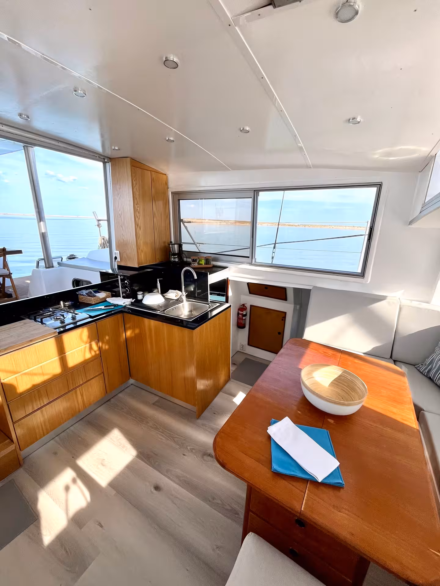 Modern catamaran cabin with kitchenette and dining table, part of Full Day Sail Catamaran Blue Lagoon tour