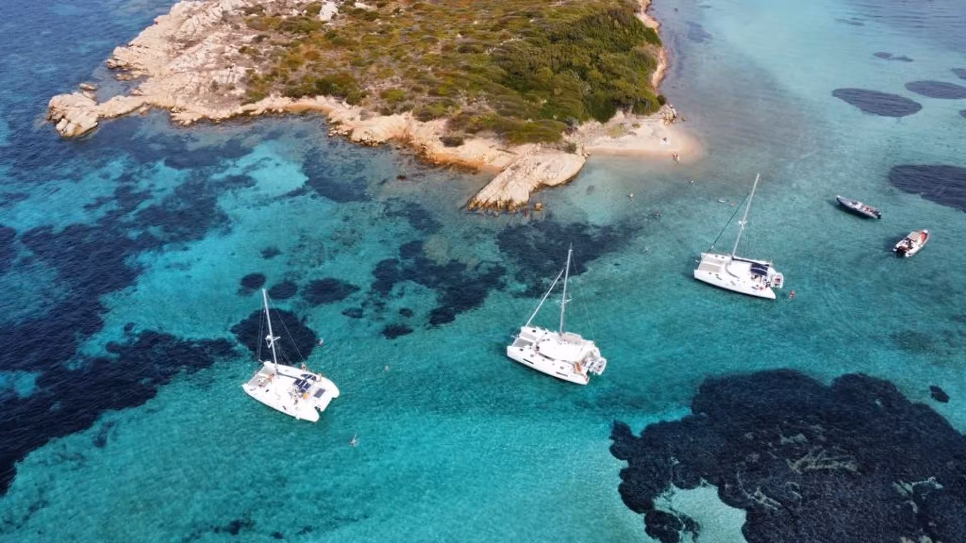 Aerial view of catamarans anchored in the vibrant waters near the islands of La Maddalena Archipelago.
