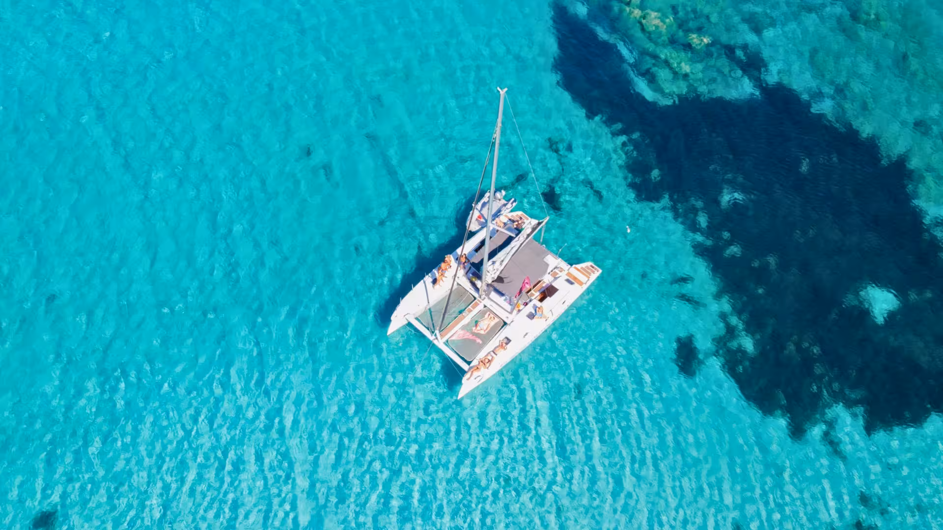 Aerial view of a catamaran sailing in the crystal-clear waters of La Maddalena Archipelago near Cannigione.