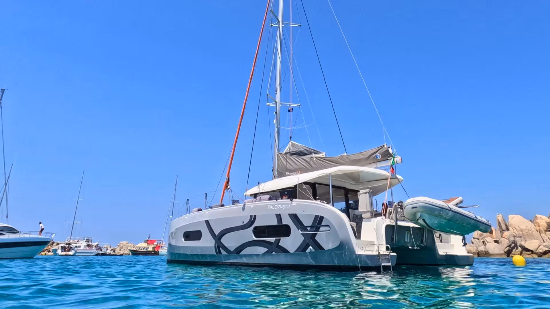 Elegant catamaran anchored in the clear blue waters of La Maddalena Archipelago, perfect for a scenic excursion.