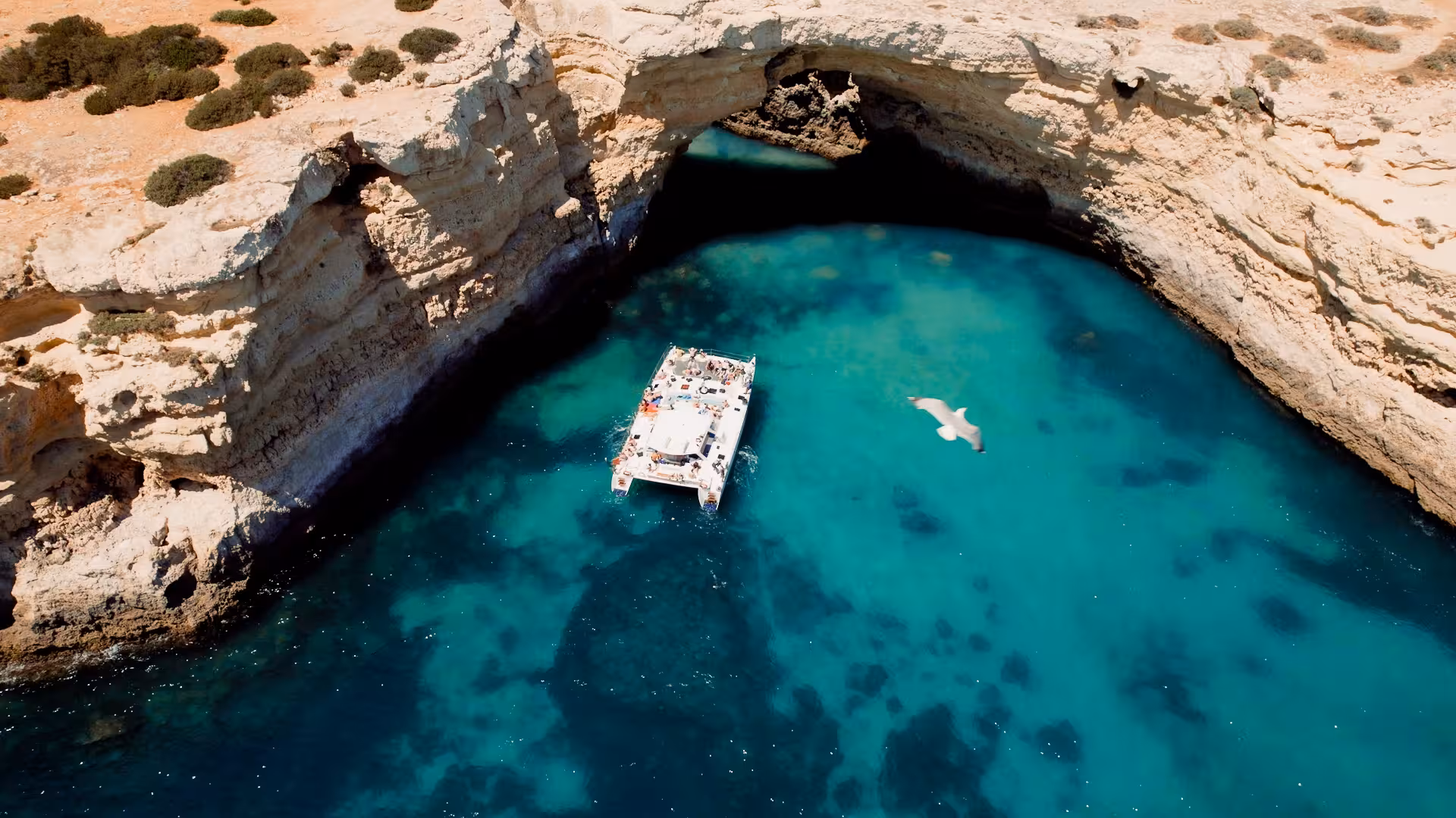Aerial view of catamaran exploring stunning turquoise waters and rock formations on the 'Catamaran MARA' tour.