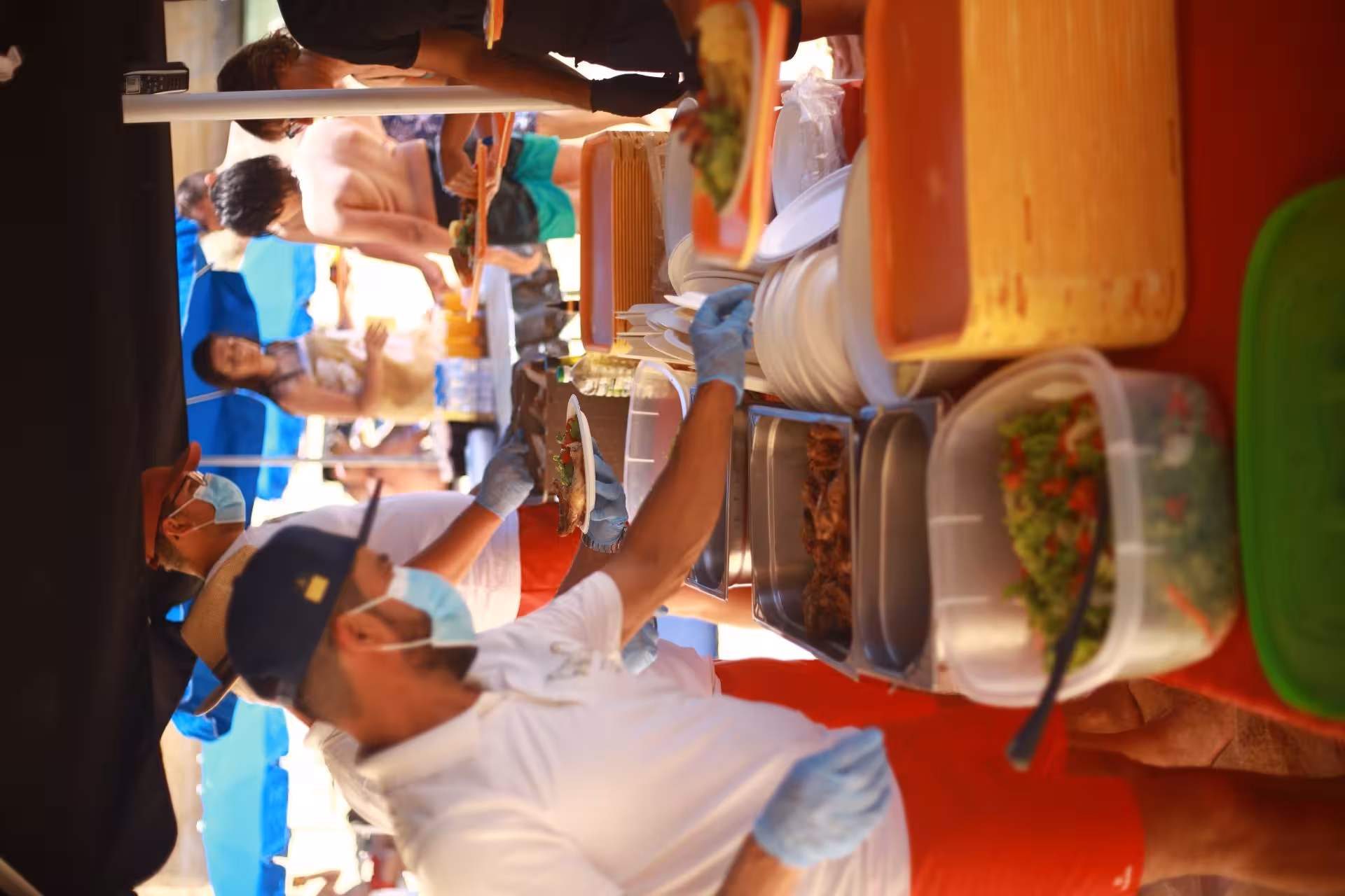 Crew members serve fresh BBQ dishes to guests under umbrellas on the Catamaran Ophelia Benagil Caves tour.