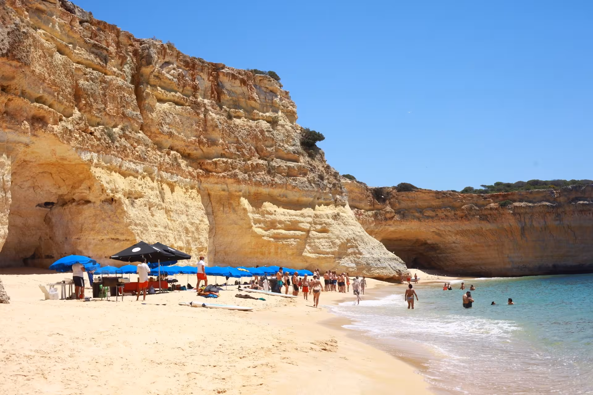 Sunny beach with visitors enjoying the golden sands and turquoise waters near Benagil Caves, ideal for a BBQ stop.