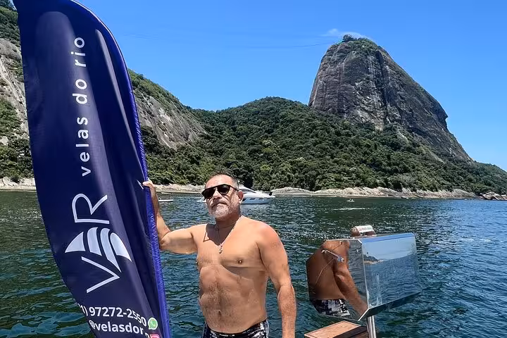 Guest by Velas do Rio flag on catamaran near Sugarloaf Mountain, private 5-hour sail with BBQ and open bar