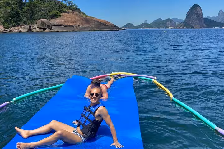 Relaxing on floating mat in Guanabara Bay on Velas do Rio private catamaran tour with open bar