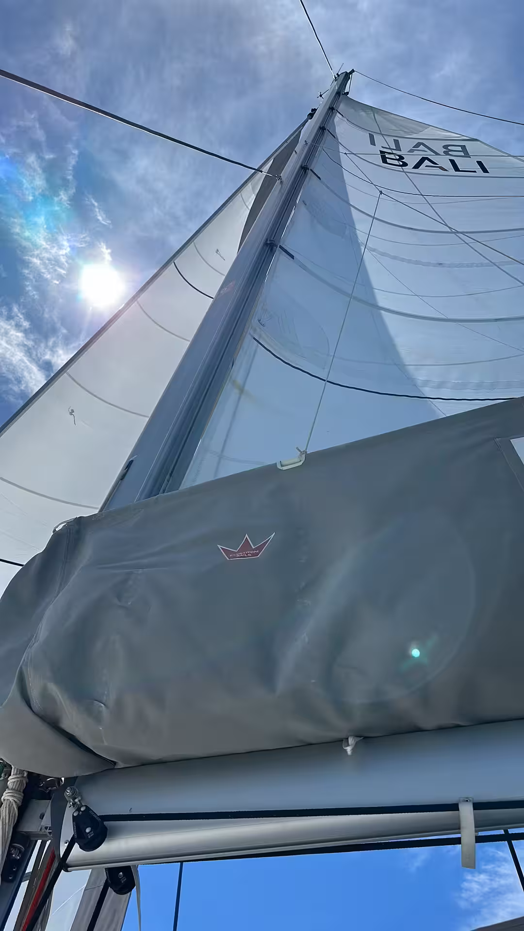 Catamaran sail and mast close-up under blue sky, hands-on multi hull sailing course training