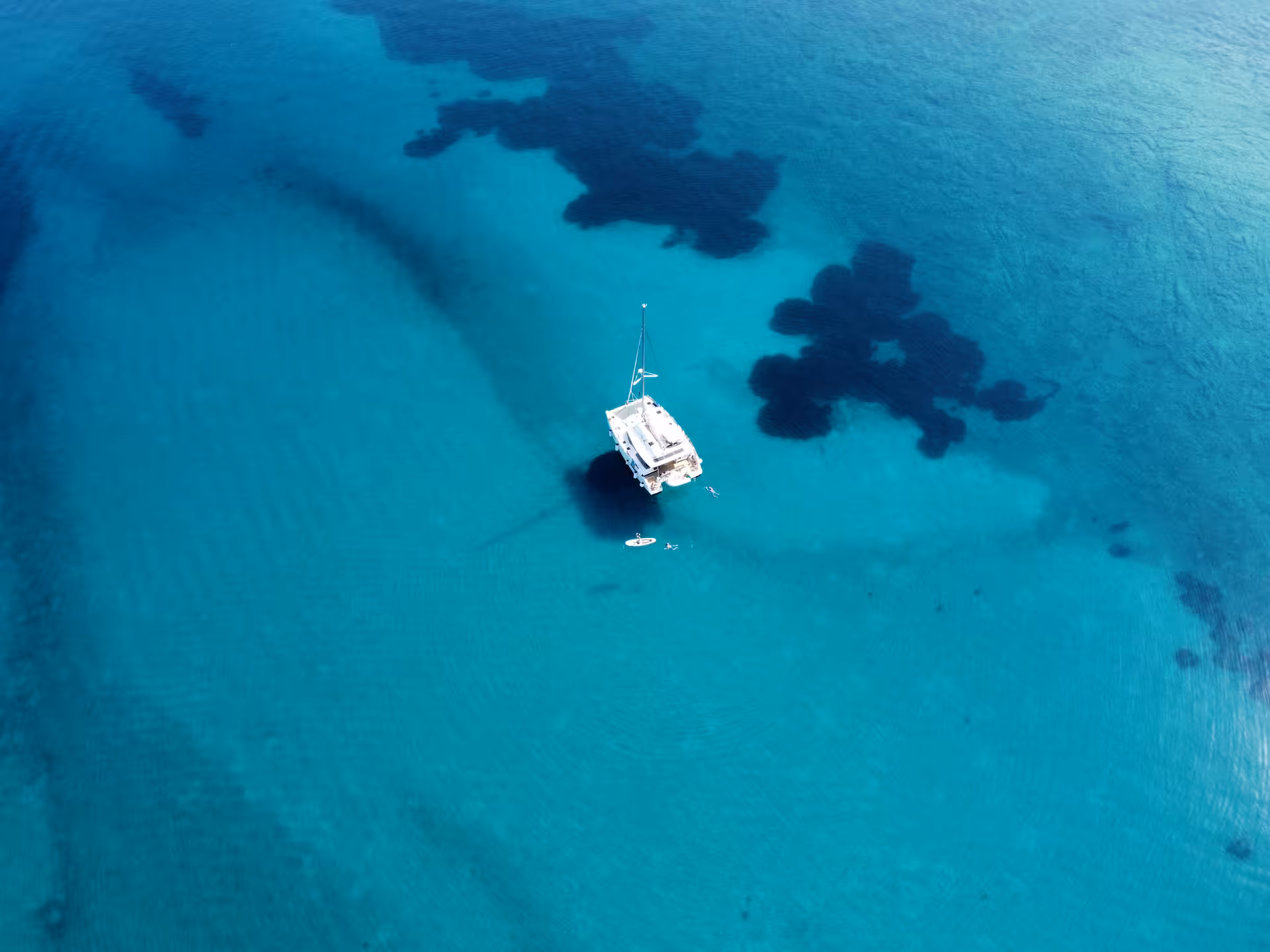 Catamaran anchored in crystal-clear blue water for a Dolce far niente sailing day with swimming and SUP