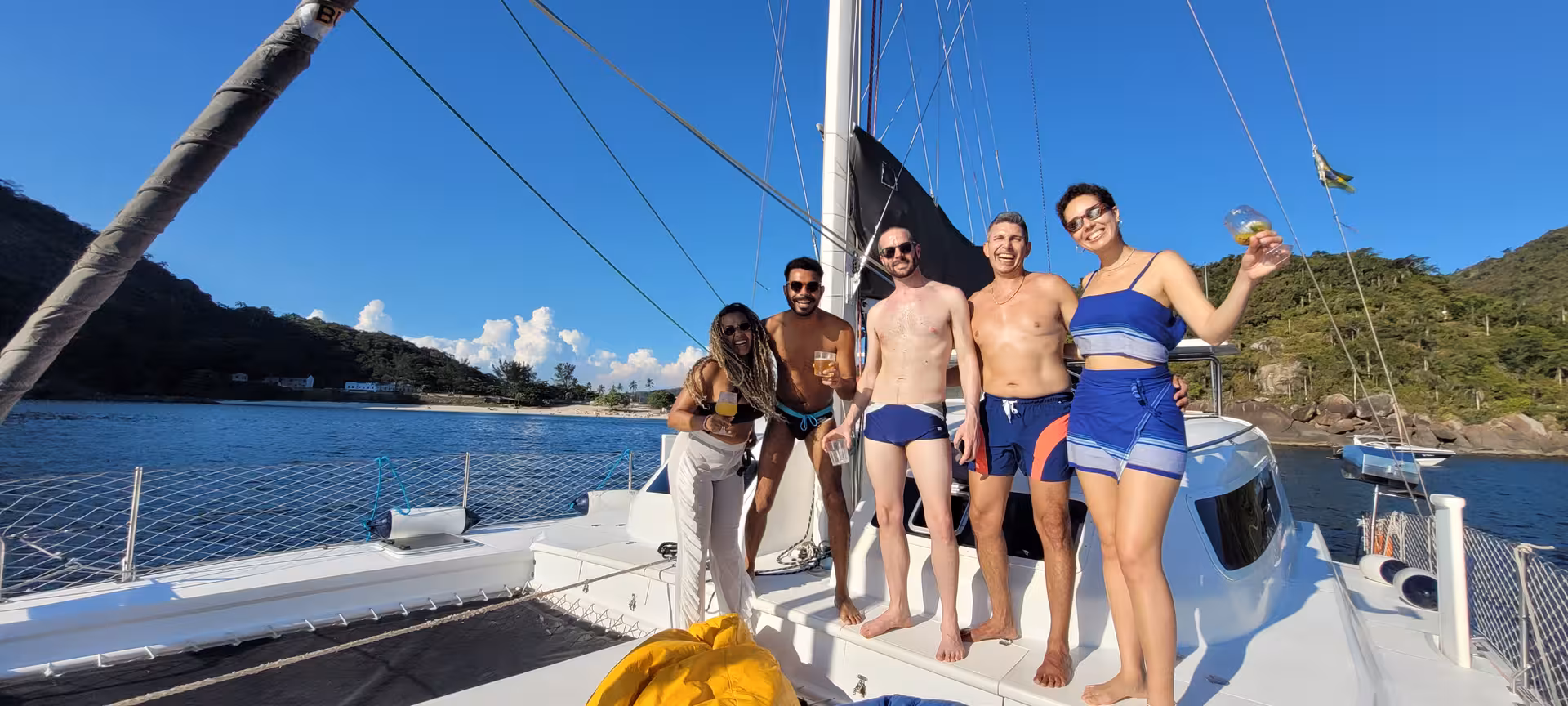 Friends enjoying drinks on a catamaran during the 3-hour Velas do Rio shared sailing tour in Rio