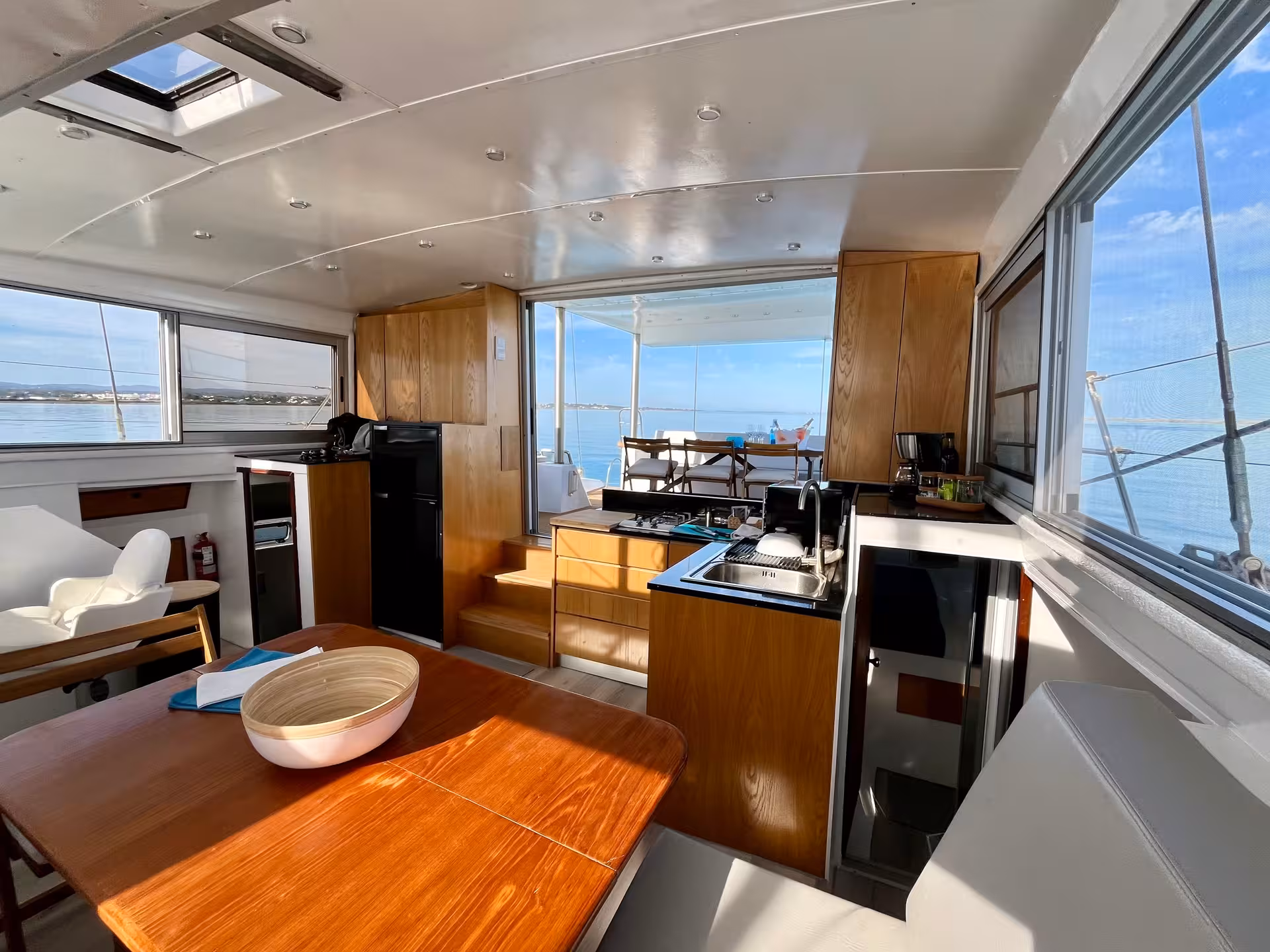 Spacious catamaran saloon with dining table and sea-view windows on Malta full-day Blue Lagoon cruise