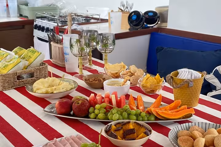 Onboard snacks and fruit spread with wine glasses on catamaran, Velas do Rio shared sailing tour