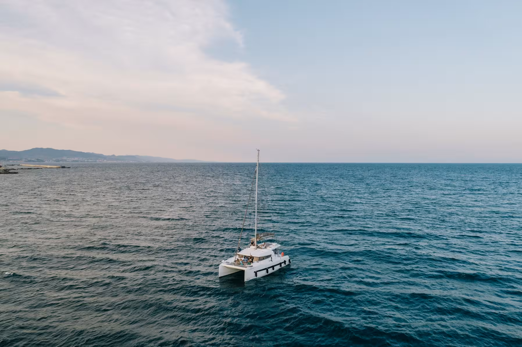 Private catamaran sailing on calm ocean at sunset, ideal marriage proposal boat tour with stunning sea views