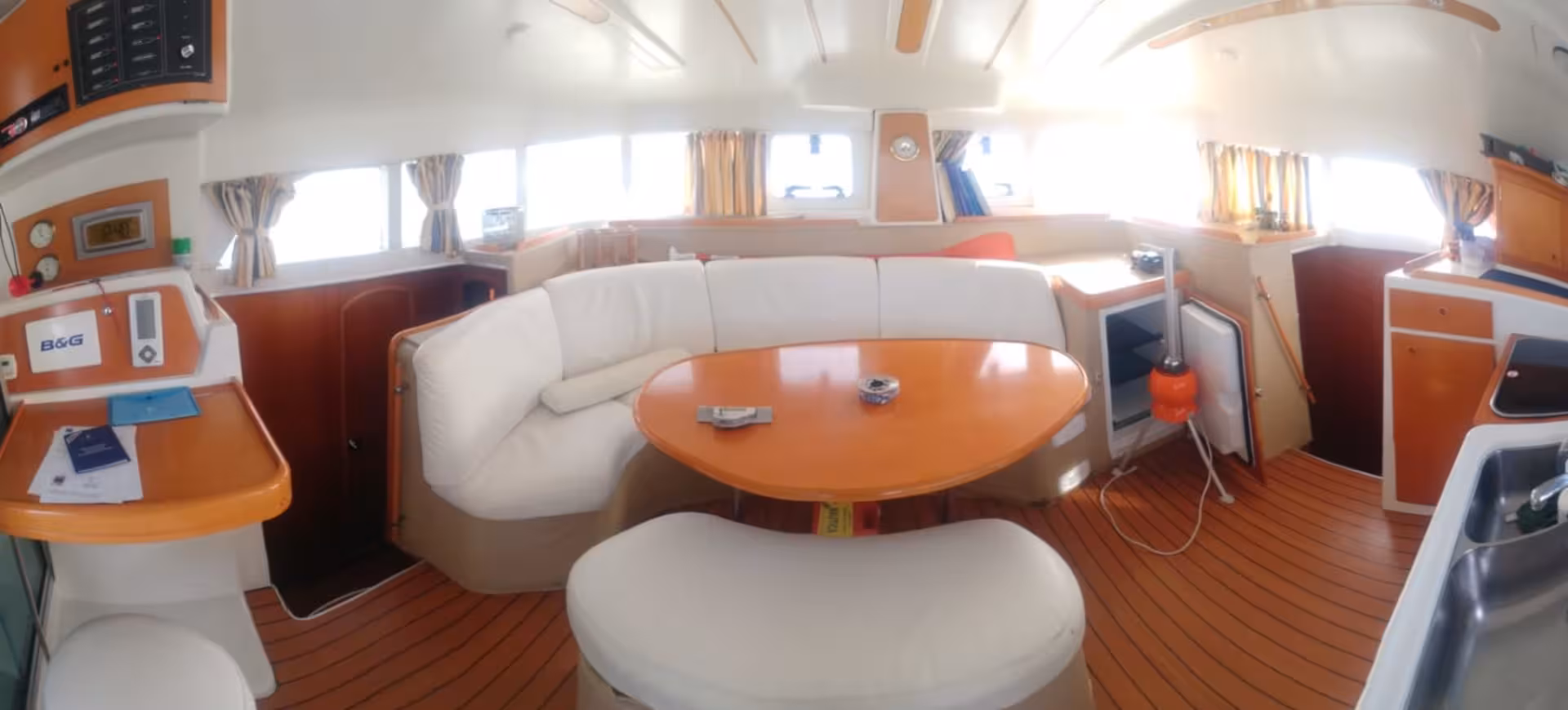 Spacious interior of catamaran Tenerè featuring a cozy lounge area with a round table and panoramic windows.