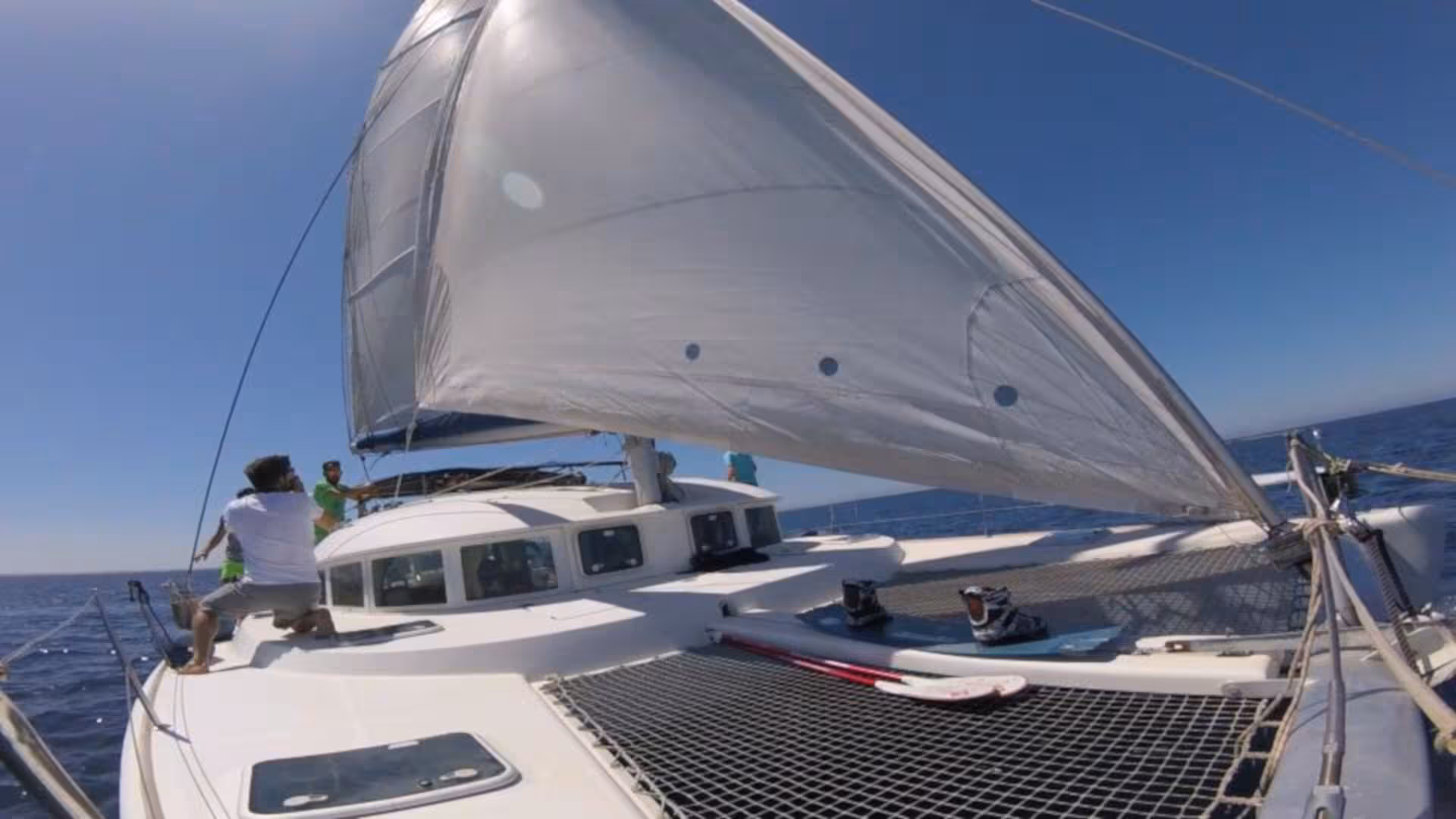 Sailing adventure on Catamaran Tenerè in La Maddalena Archipelago with crew adjusting sails under clear blue skies.