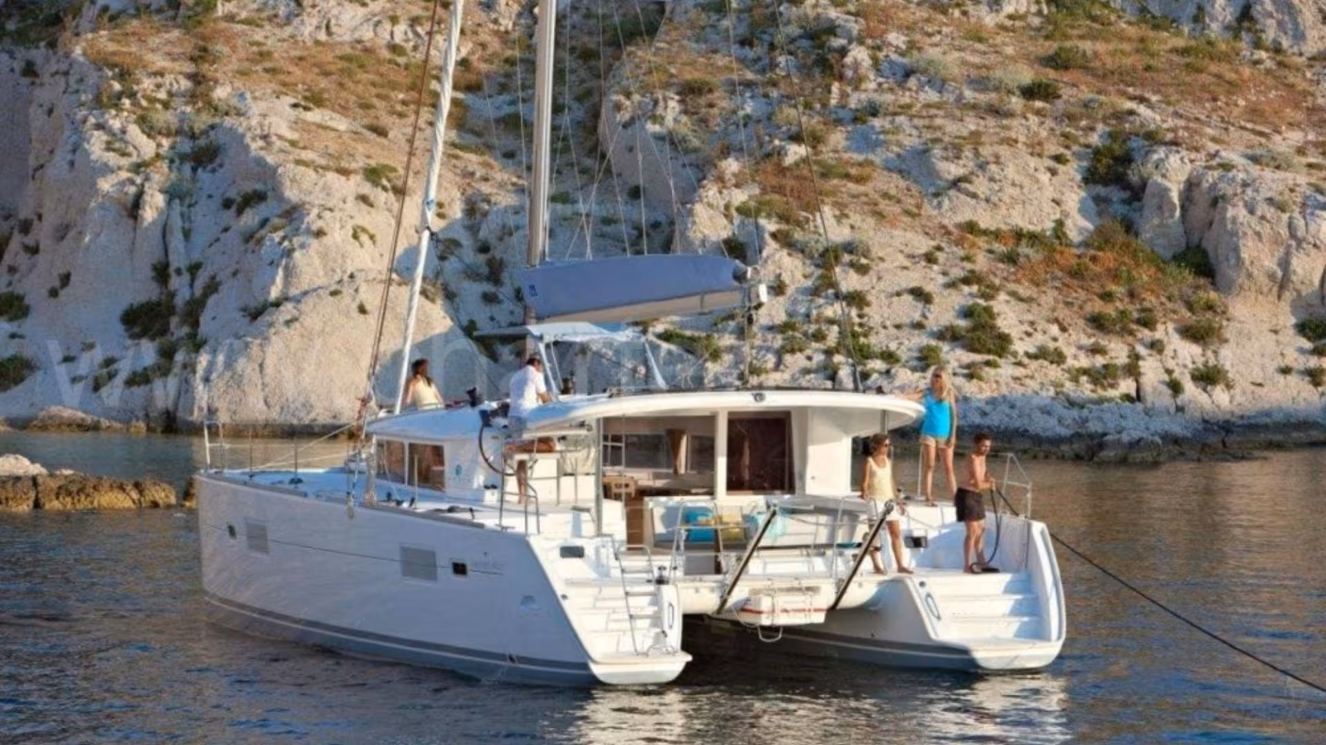 Luxurious catamaran anchored near Tavolara cliffs, perfect for marine tours from Olbia with stunning views.