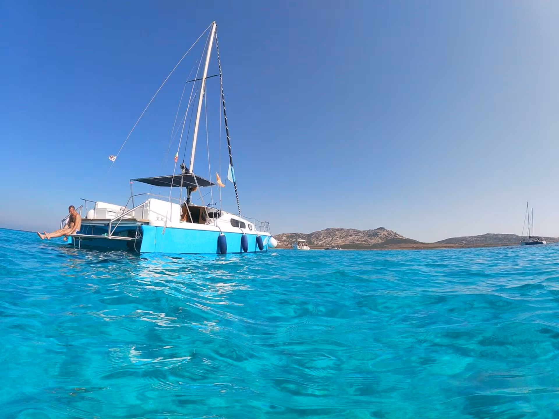 Relax on a blue catamaran cruising the crystal-clear waters of the Gulf of Asinara near Stintino, Sardinia.
