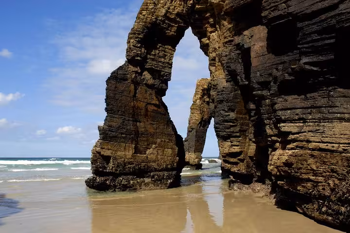 Stunning rock arches at Catedrais Beach with clear blue skies and waves in Galicia, perfect for coastal exploration.