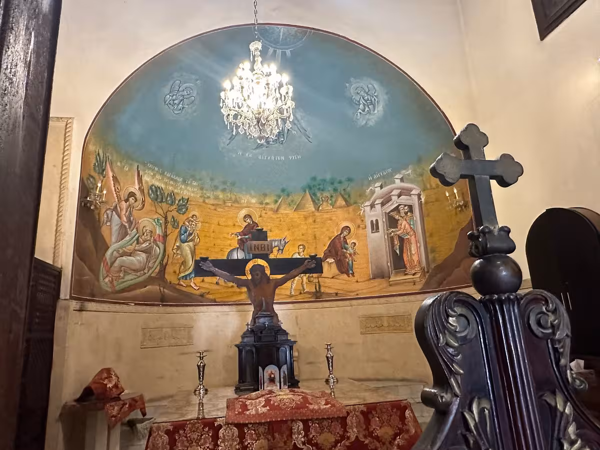 Old Cairo Coptic church altar with crucifix, chandelier, and biblical mural on Cave Church of Saint Simon tour