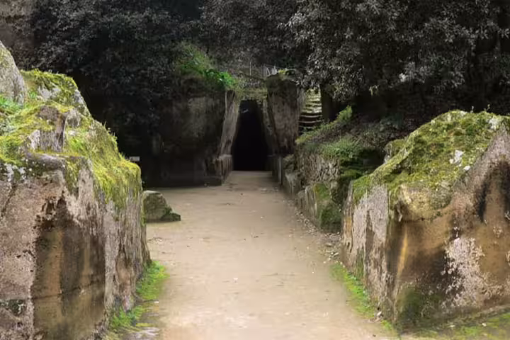 Ancient moss-covered stone passage leading to the Cave of the Sibyl in Cuma, visited on private tours from Naples to Phlegraean Fields