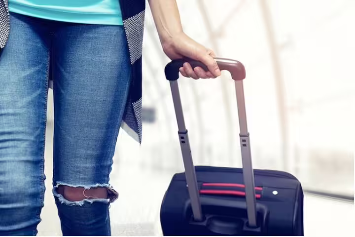 Passenger rolling suitcase in airport hallway, meet-and-greet private transfer from CDG Airport to Paris hotel