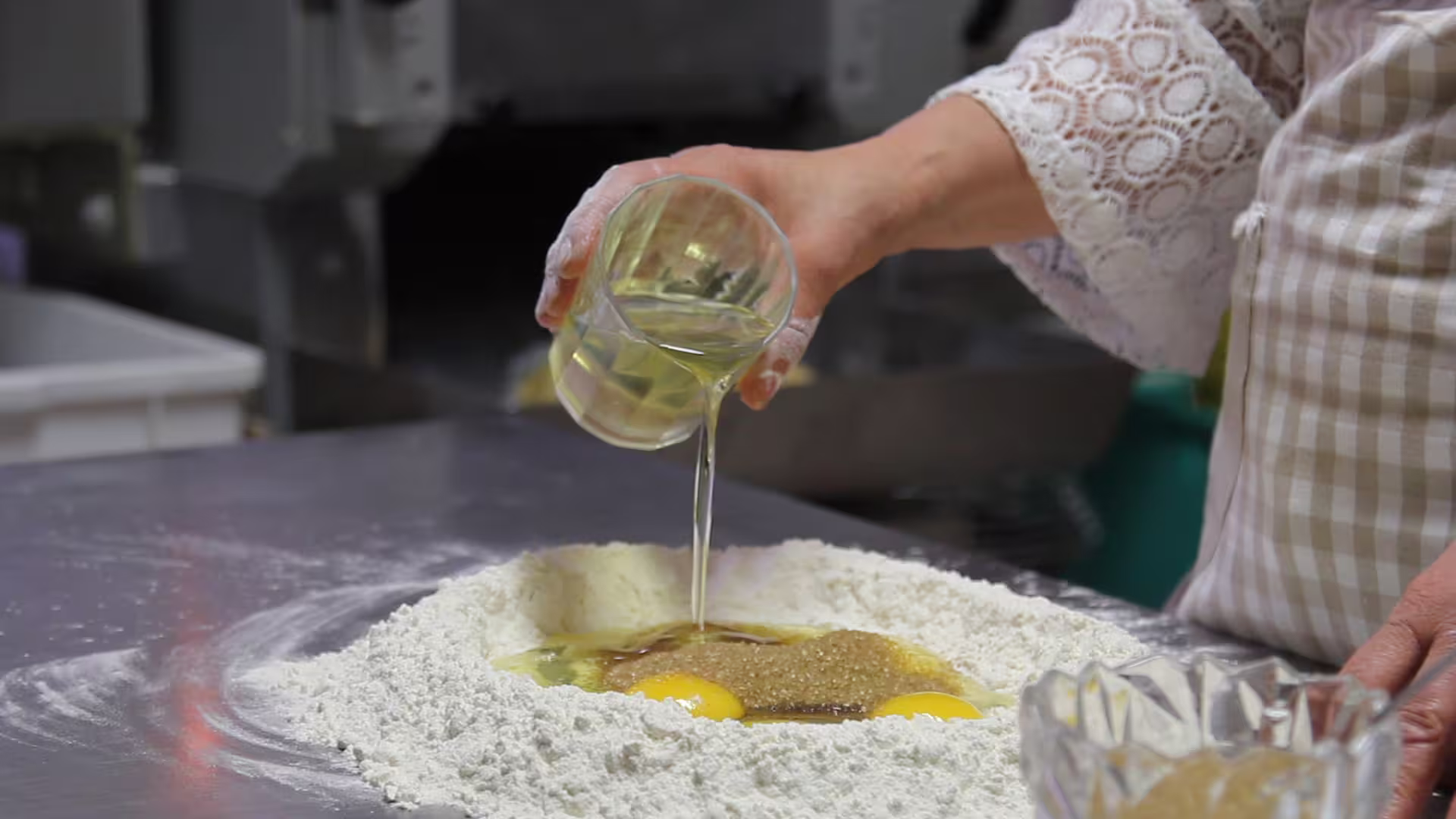 Chef pours oil into flour well with eggs and sugar during Cecio Ripieno show cooking, hands-on class