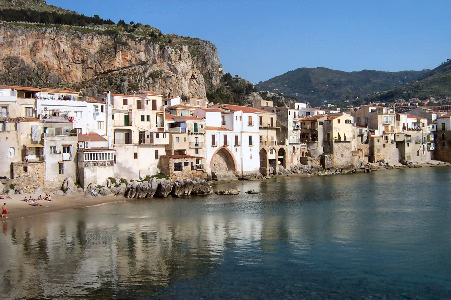 Cefalù old fishing quarter by the sea with stone houses and calm bay, Sicily day trip with wine tasting