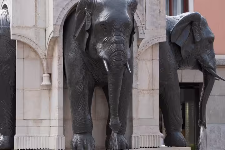 Large bronze elephant statues standing before arched stone building facade in Chambery