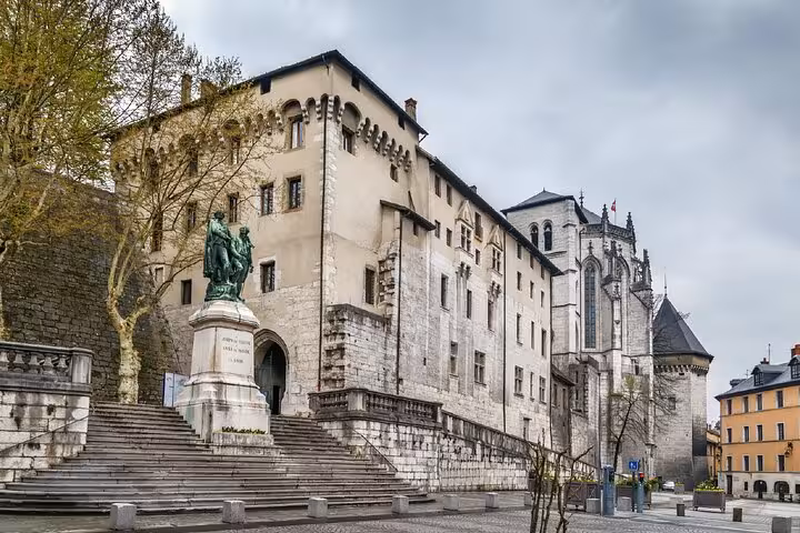 Chambery castle and cathedral with bronze statue on stone steps in historic town square
