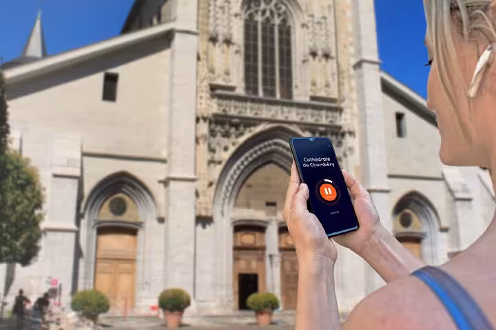 Tourist using audio guide app on smartphone in front of Cathédrale de Chambéry, France