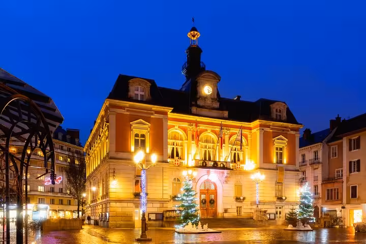 Chambery Town Hall illuminated at night with Christmas trees and festive lights in the main square